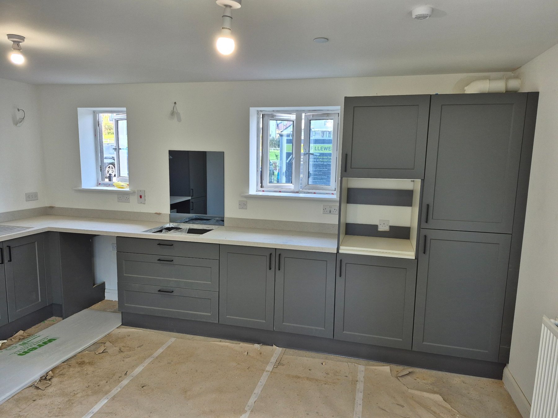 Dark grey kitchen cabinetry during installation, with fitting work in progress